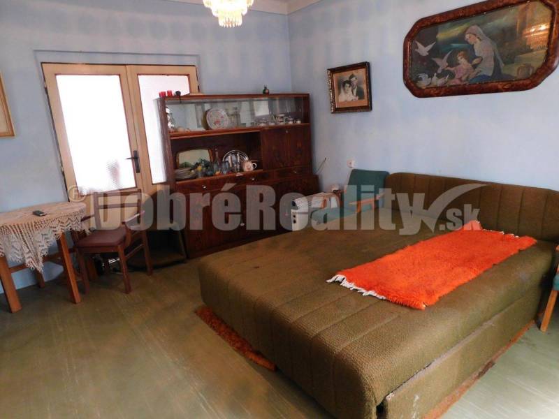 Living room with a bed, showcase, and table; Family house decorated with artworks.