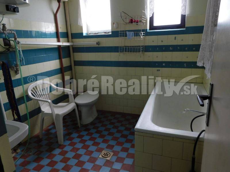 Bathroom in a family house with a bathtub, sink, toilet, and plastic chair.