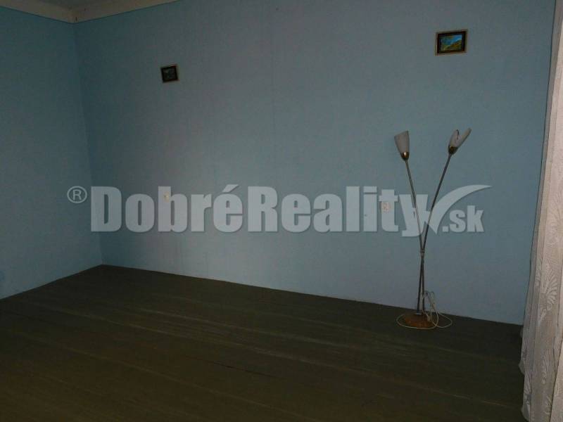 A room in a family house with blue walls, a standing lamp, and small pictures.