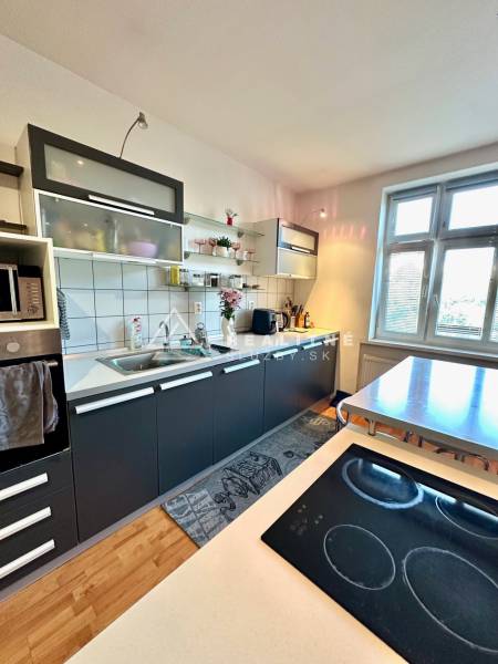 Kitchen in a 2-room apartment with a kitchen unit, table, and cooktop.