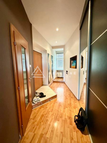 A hallway with a wooden floor and a wardrobe in a 2-room apartment, decorations on the walls.