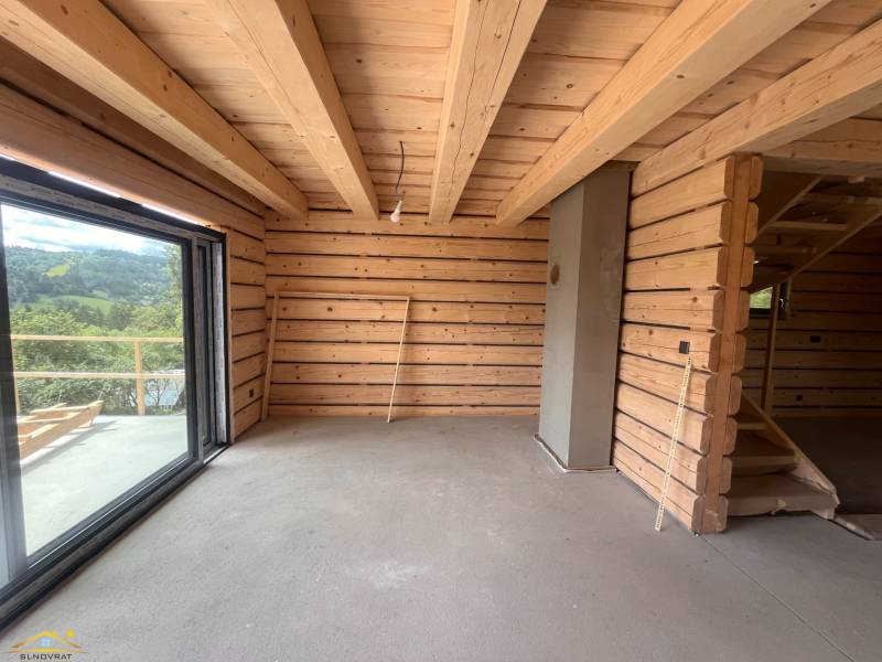 Interior of a wooden cabin with a large window and a staircase.