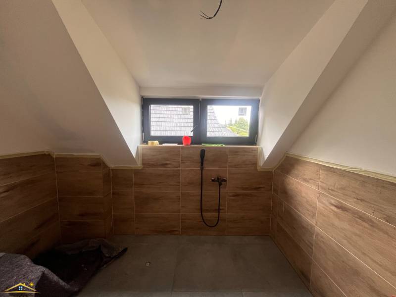 An attic bathroom in a cabin with wooden paneling and a skylight.