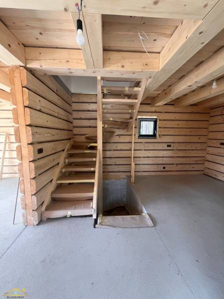 Wooden interior of a cabin with a concrete floor and staircase.