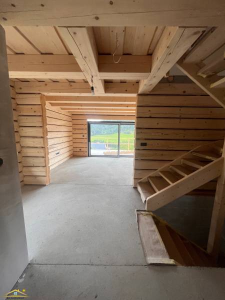 A cabin with a wooden interior, staircase, and glass view of the surrounding nature.