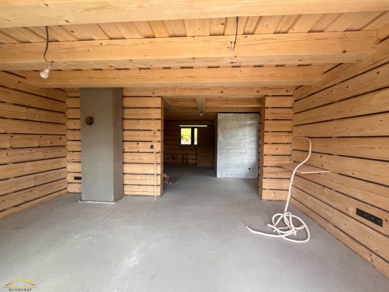 A wooden interior of a cabin with a concrete floor and unfinished elements.