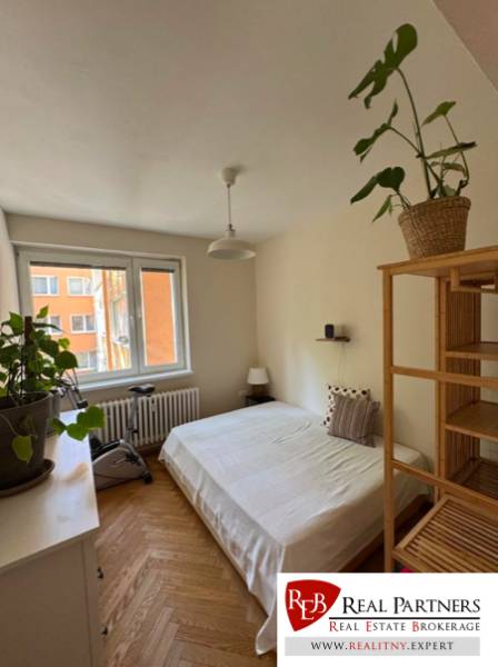 A bright bedroom with greenery and an exercise machine in a 4-room apartment.