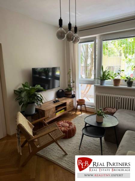 Living room with a sofa, TV, and houseplants in a 4-room apartment.