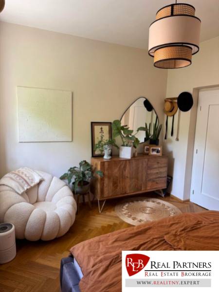 Elegant room with a light armchair, wooden dresser, and houseplants in a 4-room apartment.