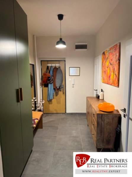 A hallway in a 4-room apartment with dark tiles, wooden furniture, and decorations.