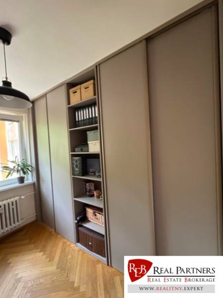 A wardrobe in a 4-room apartment with wooden flooring and shelves for storage.