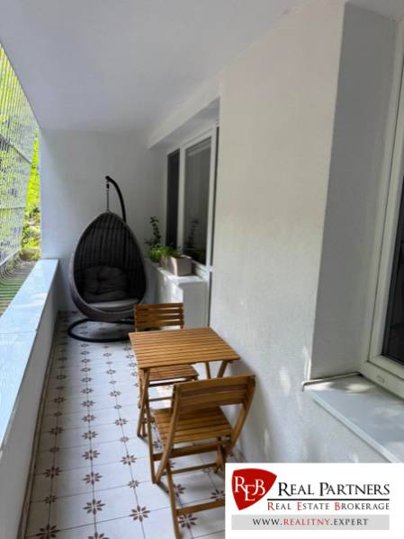 Glazed balcony of a 4-room apartment with seating and a hanging chair.