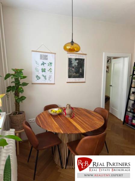 Dining area with a table and chairs in a 4-room apartment with plants on the wall.