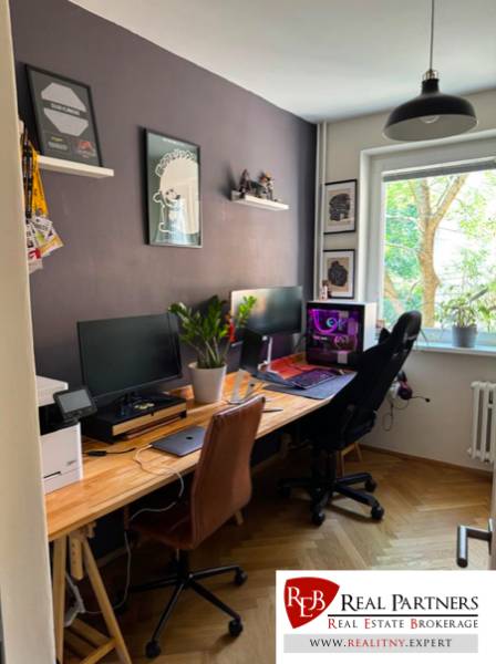 A workspace with computers and a plant by the window in a 4-room apartment.