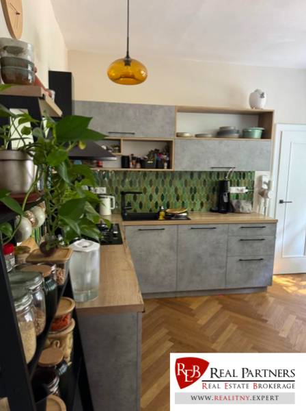 A kitchen in a 4-room apartment with wooden flooring and green tiles.