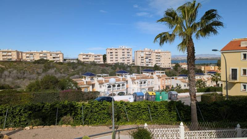 A view of residential buildings, trees, and containers on Aquiles Street in Torrevieja.