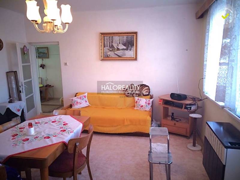 Living room of a family house with a dining table, sofa, and a radio on a shelf.