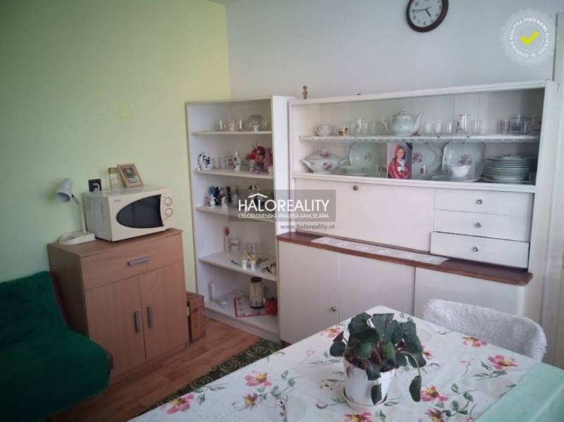 Interior of a family house with retro furniture, a microwave, and a dining table with a floral tablecloth.
