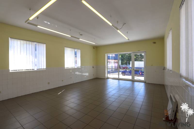Interior of commercial spaces with tiled floors, white walls, and large windows.
