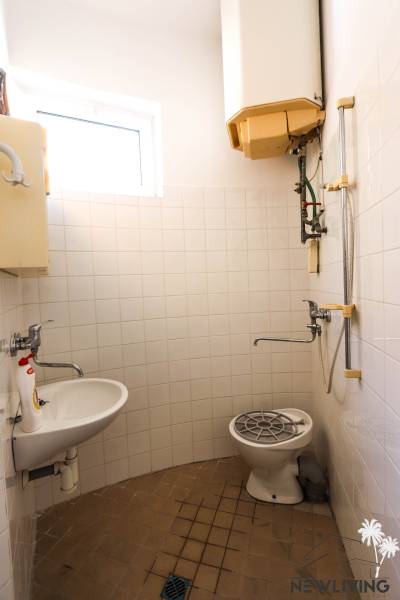 Bathroom in commercial premises with a shower, sink, and window.