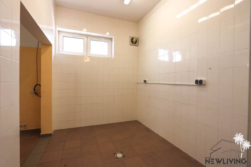 A tiled room with two windows and a fan in commercial premises.