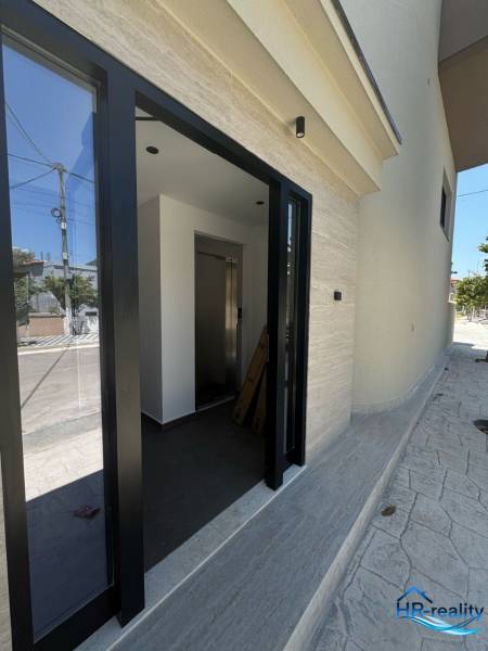 The entrance to the Recreational Apartment in Ksamil has glass doors and a bright interior.