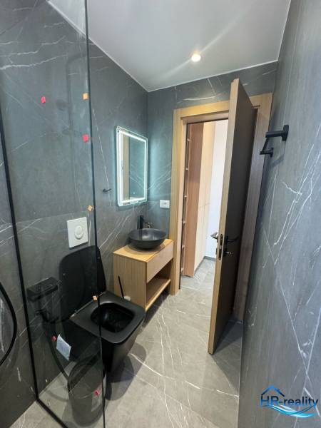 A bathroom in a holiday apartment with black sanitary fixtures and wooden furniture.