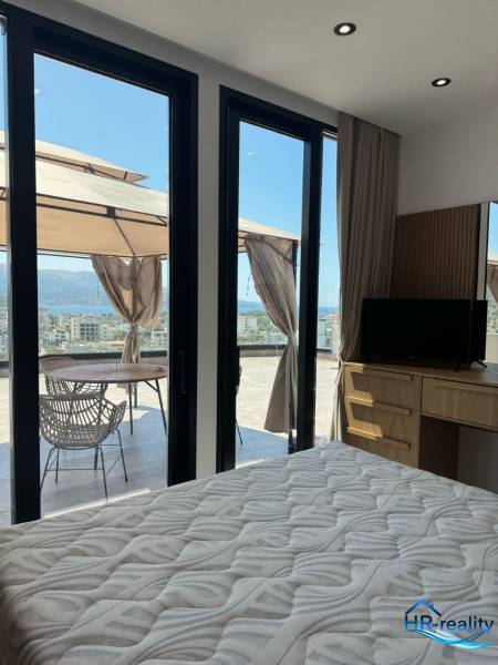 Interior of a holiday apartment with a bed, wardrobe, and a terrace with a sea view.