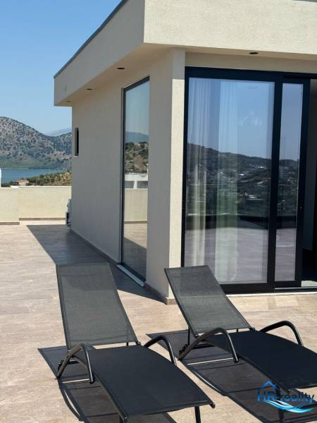 Terrace of a recreational apartment in Ksamil with a mountain view and two sunbeds.