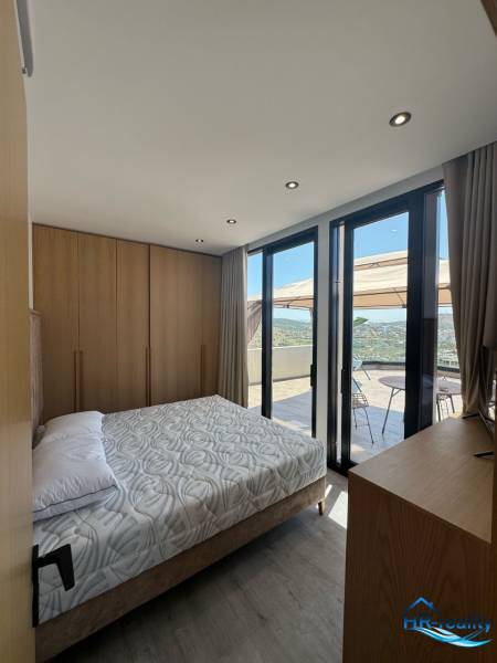 A bedroom in a holiday apartment with a view from the balcony, wooden furniture, and a bed.