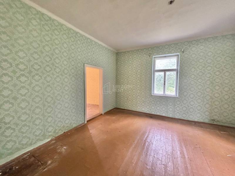 A spacious room in a family house with wallpaper and wooden flooring.