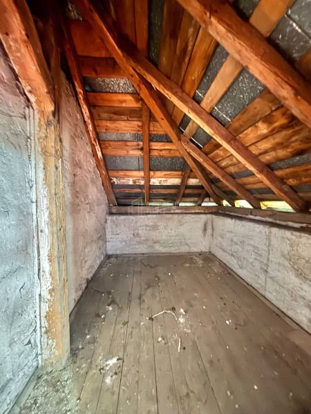 The attic of a family house with a wooden roof truss and old wooden floor cladding.
