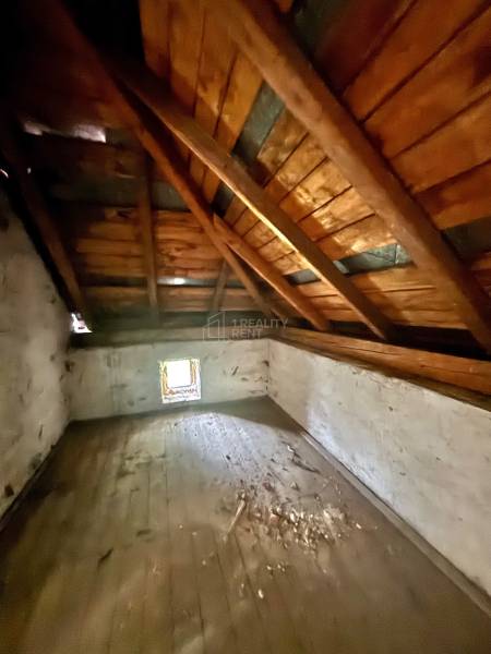 Attic space in a family house with a wooden beam ceiling and a small window.