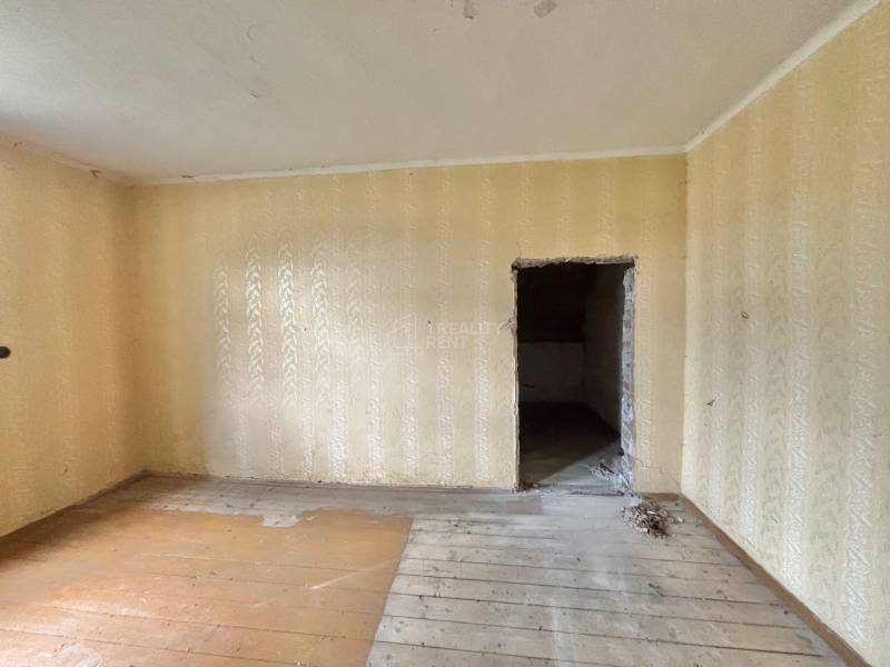 A room in a family house with a wooden floor and beige wallpaper.