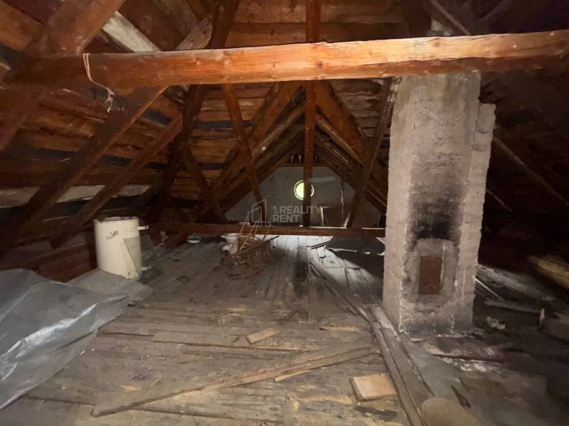 The attic of a family house with a wooden structure and a brick chimney.