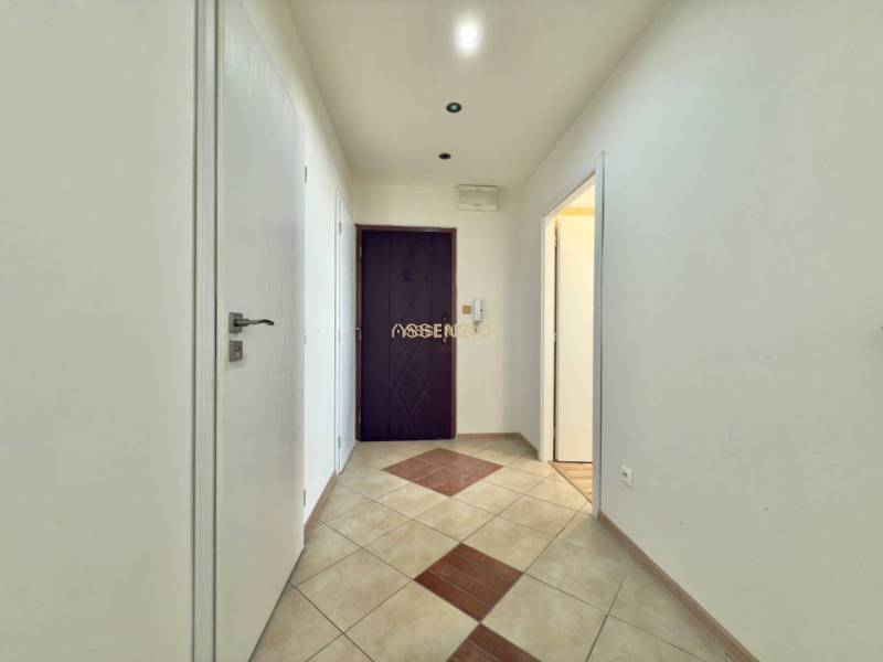 A hallway with an entrance door and tiles in a 4-room apartment.