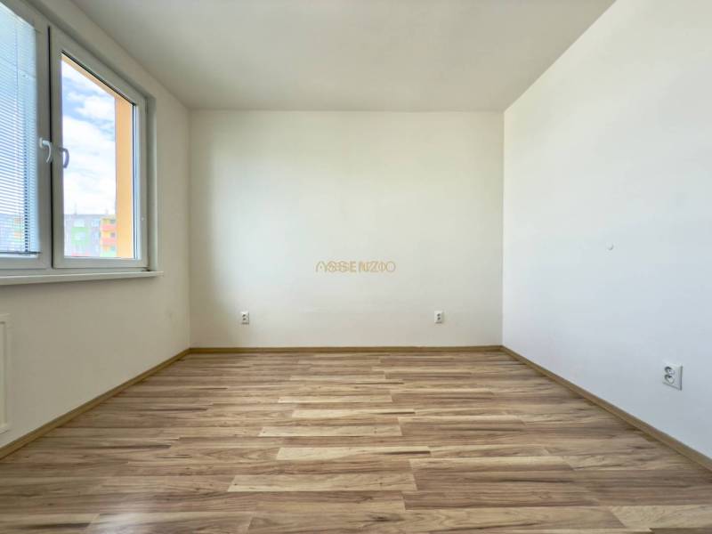 An empty bright room with wooden flooring in a 4-room apartment.