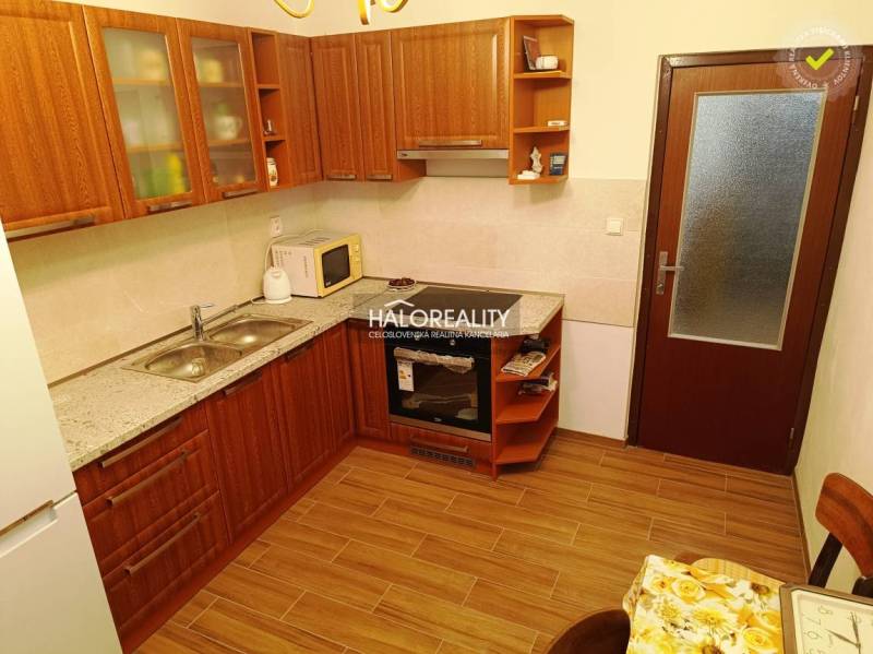 A kitchen with wooden cabinets and appliances in a 2-room apartment, optimal for cooking.