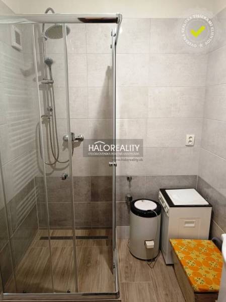 Shower corner and washing machine in the bathroom for a 2-room apartment with brown tiles.