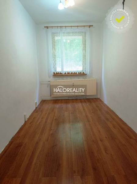 A narrow room with a wooden floor, a window, and a radiator in a 3-room apartment.