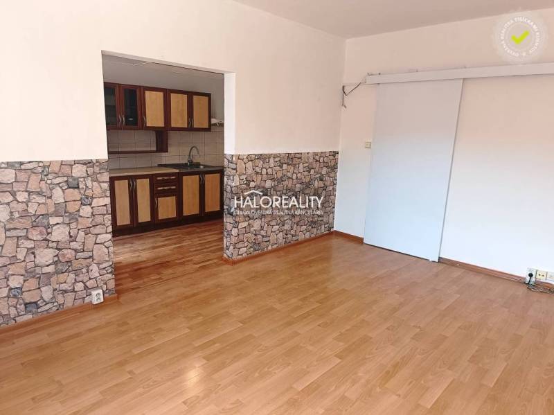 Living room in a three-room apartment with wooden flooring and a kitchenette.