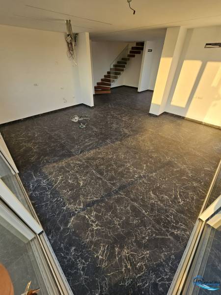 Recreational apartment with dark flooring, white walls, and a staircase.