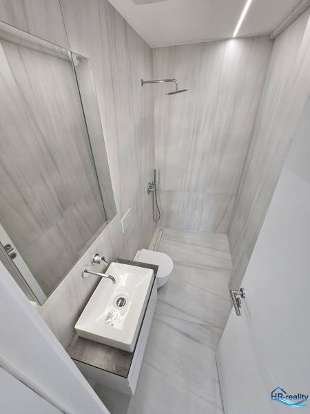 Bathroom in a holiday apartment with a shower, sink, and toilet.