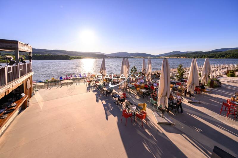 Summer terrace by the water in Ružiná, with a view of the lake and mountains.