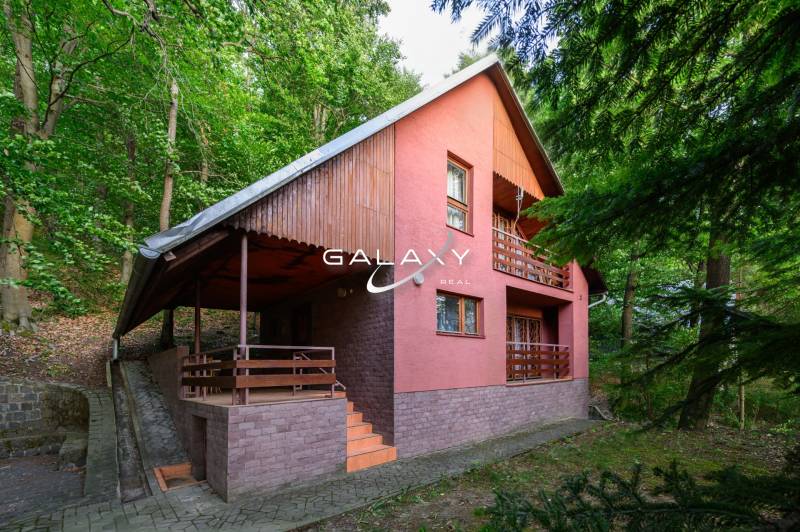 A cottage in Ružiná surrounded by greenery, featuring typical architecture and wooden details.
