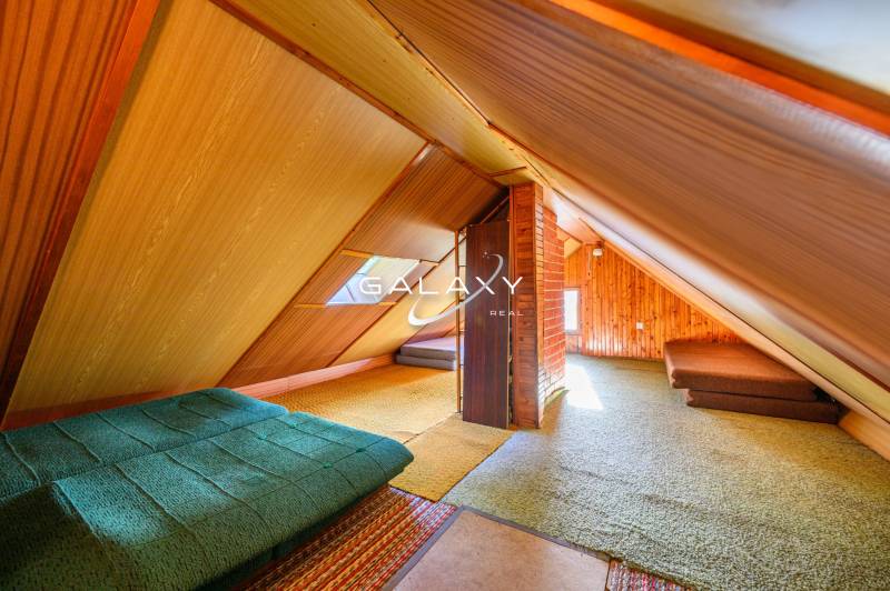 Attic in a cabin with wooden walls and sofa beds.