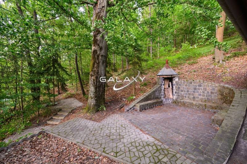 The cottage by the lake in Ružiná with a stone bench and a wooden shelter for wood.
