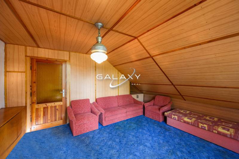 Wooden interior of a cabin with a sofa set and a blue carpet.