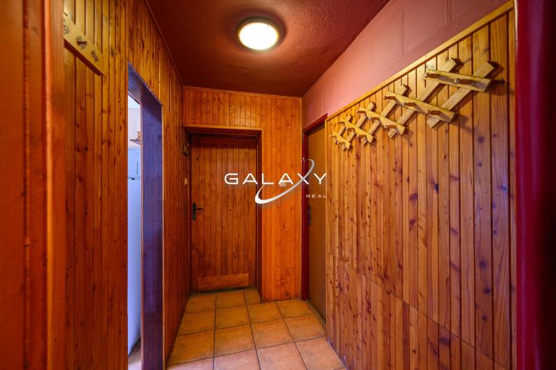 A wooden interior of a cabin with a coat rack and lighting offers a cozy atmosphere.