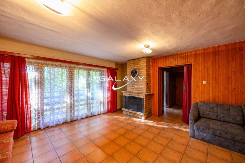 The interior core of the cottage with a fireplace, large windows, and red curtains.